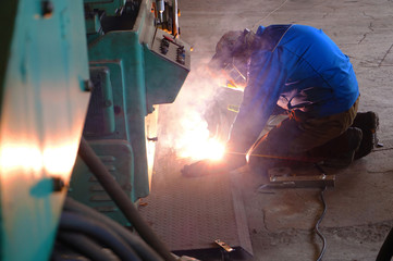 The welder at the industrial plant makes the connection using an electric arc.