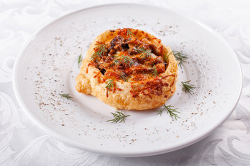 Juicy meat pie, beef stew pie with puff pastry. Homemade fresh baked, country rustic style. Pot pie with cheese on white plate