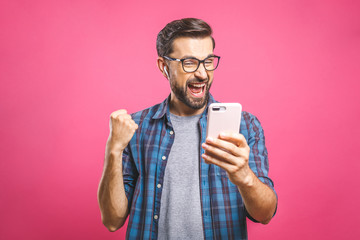 I'm a winner! Happy man holding smartphone and celebrating his success over pink background.