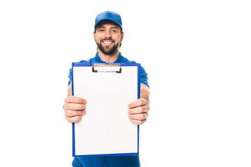 handsome young delivery man holding blank clipboard and smiling at camera isolated on white