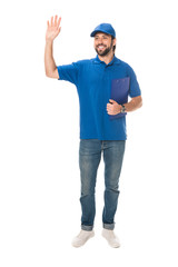 full length view of happy young delivery man holding clipboard and waving hand isolated on white