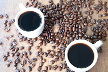 A cup of coffee and beans on wooden table background
