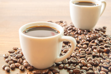 A cup of coffee and beans on wooden table background