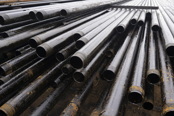 Oil Drill pipe. Rusty drill pipes were drilled in the well section. Downhole drilling rig. Laying the pipe on the deck. View of the shell of drill pipes laid in courtyard of the oil and gas warehouse.