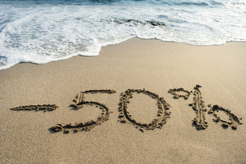 inscription on the sand minus fifty percent, 50 %, sea wave on the sand with the inscription fifty
