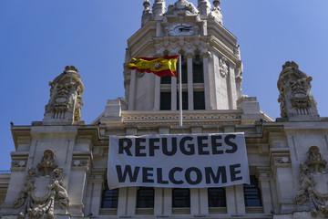 Naklejka premium Duży baner „Witamy uchodźców” Urzędu Miasta Madrytu. Na górze wisi szyld budynku Plaza de Cibeles CentroCentro.