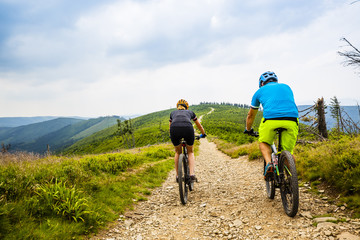 Cycling, mountain biker couple on cycle trail in autumn Mountains. Man and woman cycling MTB flow trail.