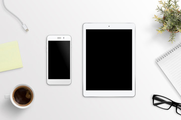 Phone and tablet on white office desk. Blank screen for mockup, app or responsive web site presentation.