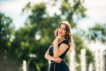 A girl is walking around the city, near a large fountain. Sunny day. Summer