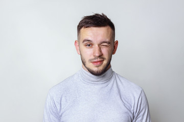 Handsome man looking at camera and winking. isolated on gray, copy space