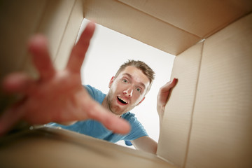 Man smiling, opening box and looking inside. The package, delivery, surprise, gift and lifestyle...