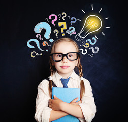 Cute child schoolgirl at the blackboard with lightbulb and colorful question marks. Problem and solution. Ideas concept