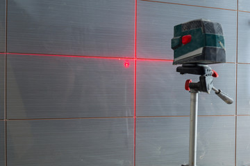 Installation of new tiles on the wall using a laser level