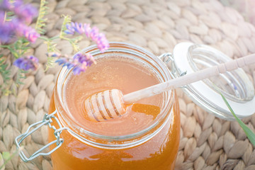a honey bank in a field with flowers. Spoon for honey.