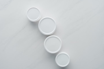 top view of bottles of cream on white surface, beauty concept