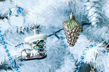 New Year's toys hanging on a white Christmas tree