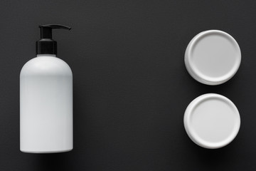 top view of bottles of lotion and cream isolated on black, beauty concept