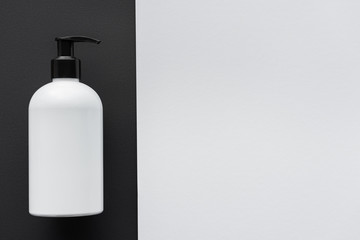 elevated view of bottle of cream on black and white surface, beauty concept