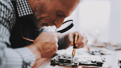 Close up. Old Man Repairing Motherboard from PC.
