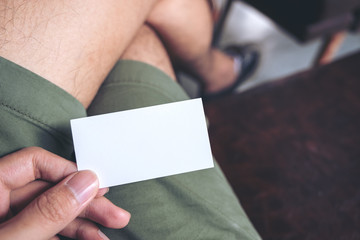 Obraz premium Top view image of a man's hand holding empty business card while sitting in cafe