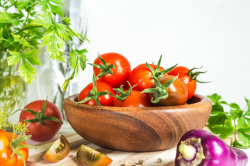 Fresh tomatoes and parsley, dill, garlic on a light background in a rustic kitchen and wooden utensils still life with a copy space