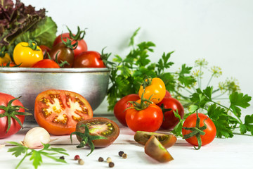 Fresh tomatoes and parsley, dill, garlic on a light background in a rustic kitchen and wooden utensils still life with a copy space