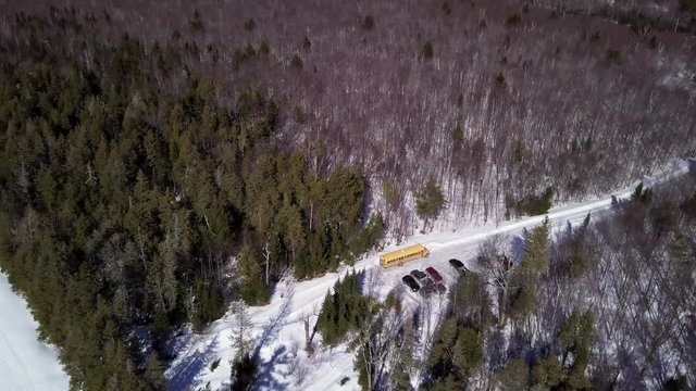 Get an aerial view of a school bus parked next to a frozen Fitzgerald Pond, Maine.