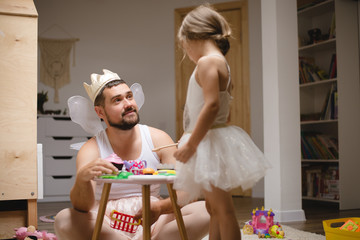 Little daughter and father have fun, dressing in princess costume, daddy makeup - obrazy, fototapety, plakaty