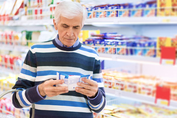 Senior man reading food label at a grocery store