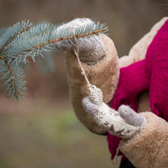 Closeup of young woman's decorating Christmas tree outdoors. Hands in mittens with Christmas decor. Christmas and winter concept.
