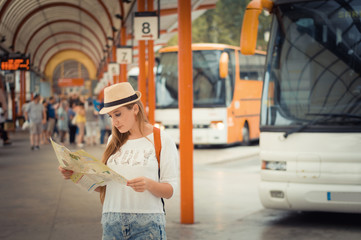 Traveler girl is waiting for a bus at the bus station. Trip to Europe. Travel and active lifestyle concept.