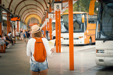 Traveler girl is waiting for a bus at the bus station. Trip to Europe. Travel and active lifestyle...