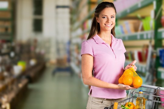 Woman with cart shopping and holding buttle in supermarket