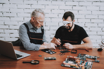 Two Men Repairing Mobile Phone in Modern Workshop.