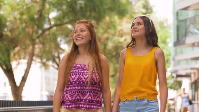 leisure and friendship concept - happy smiling teenage girls or friends walking in summer park
