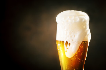 A glass of beer on a dark background.
