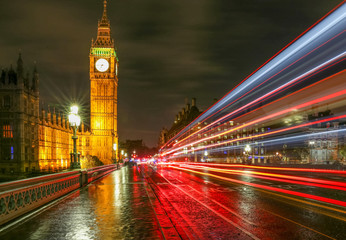 Fototapeta premium Streaks From Cars and Buses on Westminster Bridge and Houses of Parliament at Night After Rain England