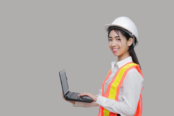 Beauty confident young Asian worker with safty equipment carrying laptop on gray isolated background.