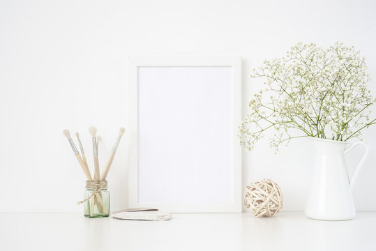 Stylish white frame mockup A4 in interior. Frame mock up background for poster frame for bloggers, social media, lettering, art, design. Indoor, frame on table with white flowers in vase. Summer sea