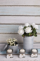 Florero vintage con rosas blancas y velas en portavelas de cristal.