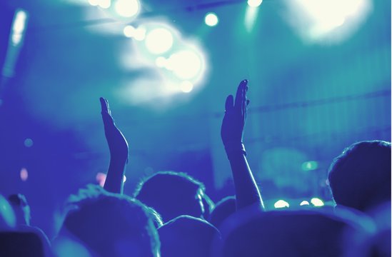 Audience with hands raised at a music festival and lights