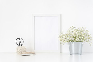 White frame mockup A4 in interior. Frame mock up background for poster or photo frame for bloggers, social media, lettering, art and design. Indoor, frame on table with flowers in metal bucket.