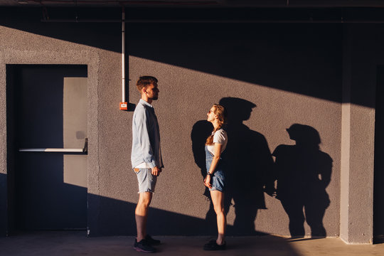 A couple holding hands standing near parking wall