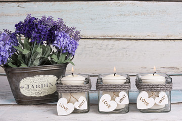 Flores de lavanda en macetero vintage y velas encendidas.