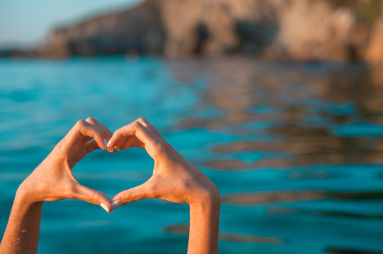 Sea love. Hands in heart shape at blue sea background
