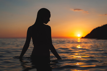 wet woman sunset silhouette in water. Sea bathing at dawn