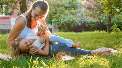 Happy family of young sporty mother and little cute daughter having fun outdoors