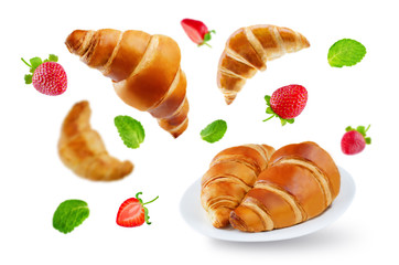 Flying croissants with strawberries and mint leaves isolated