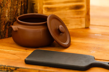 Dirty ceramic pot on old wooden kitchen board
