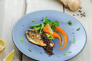 Delicious grilled seabass fish fillet steak with vegetables. Healthy meal made of seafood fish and vegetables on a table.